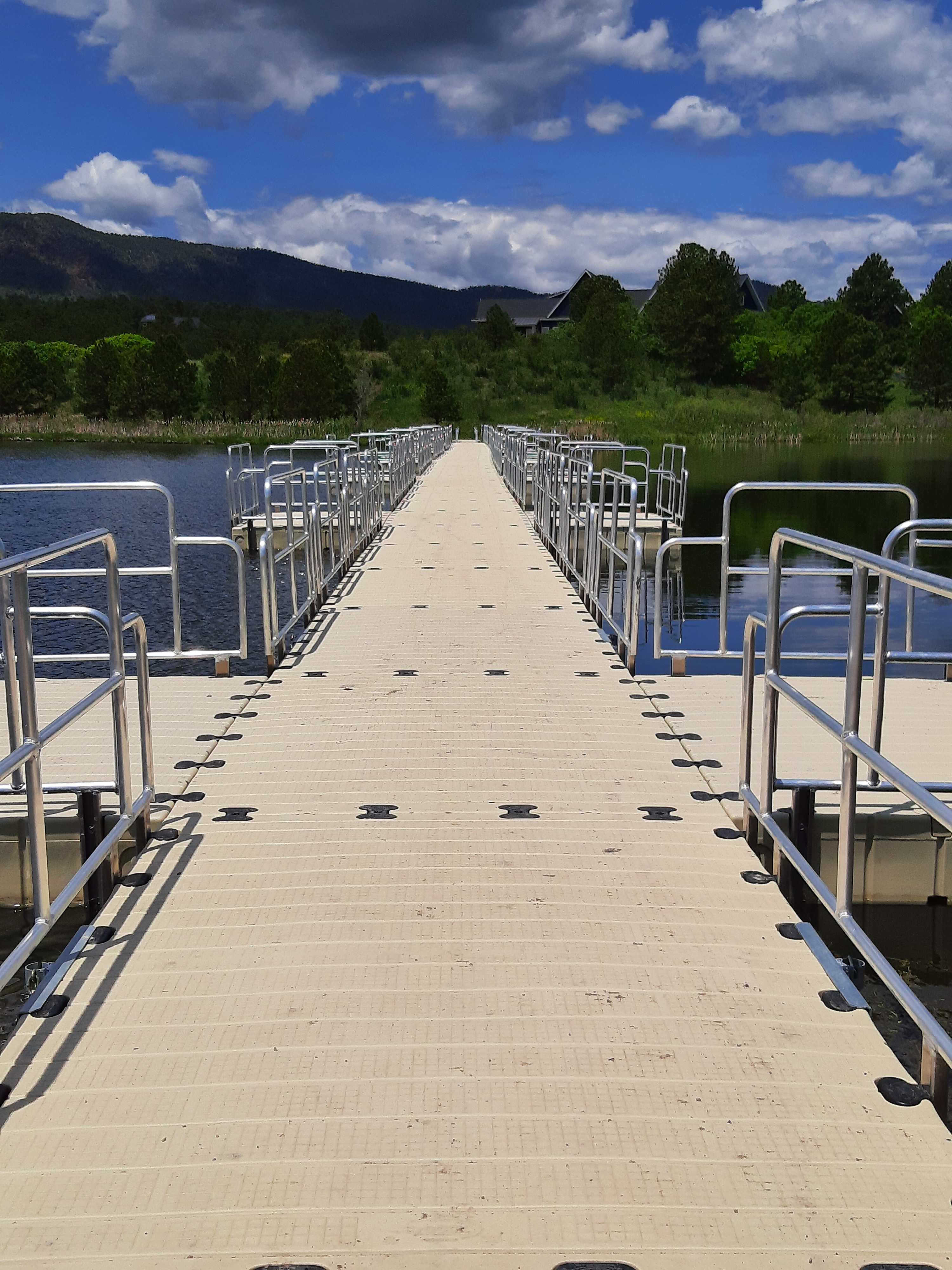 Wide floating dock system with aluminum safety rails extending into Monument Lake
